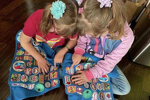 Daisy Girl Scouts showing eachother the patches on their vests